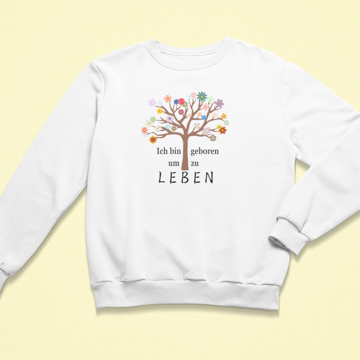 Weißes Kinder-Sweatshirt mit der Aufschrift „Ich bin geboren um zu leben“, begleitet von einem bunten Lebensbaum mit vielen farbigen Blüten. Das Design strahlt Lebensfreude, Selbstwert und Achtsamkeit aus.