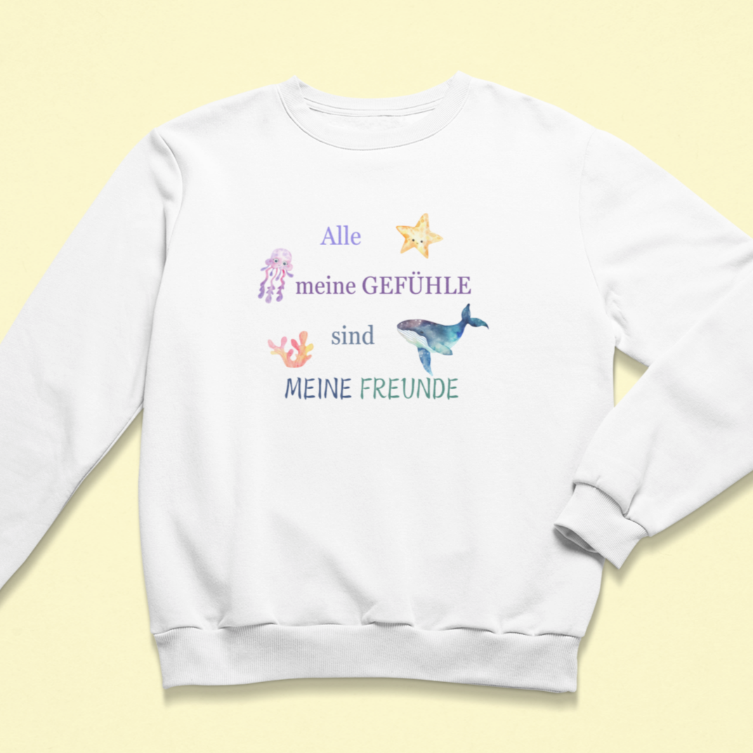 Weißes Kinder-Sweatshirt mit dem Aufdruck „Alle meine Gefühle sind meine Freunde“ in bunten Farben, verziert mit liebevollen Meeresmotiven wie Qualle, Seestern, Wal und Koralle. Das Design fördert emotionale Achtsamkeit und Selbstannahme.