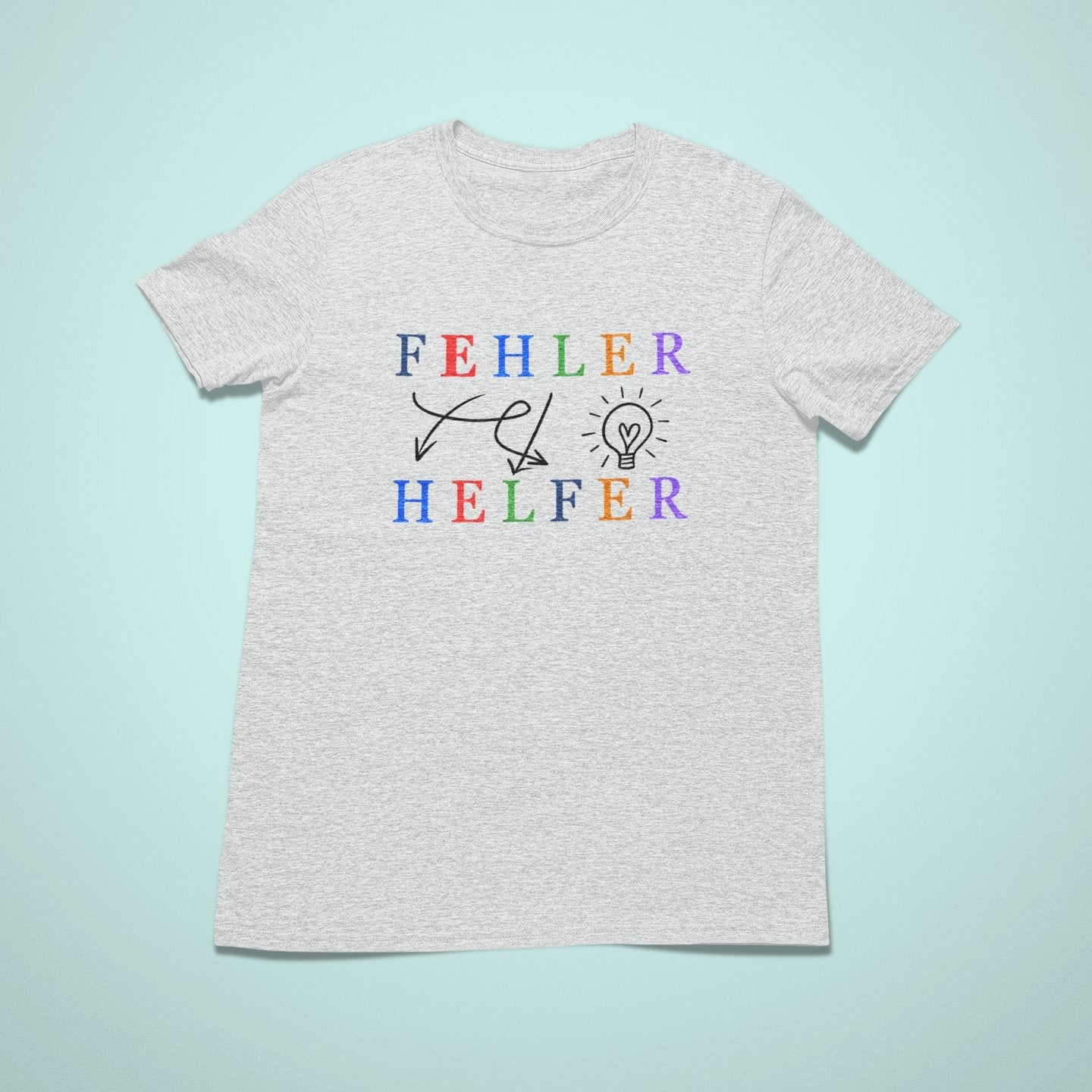 Kindershirt in Hellgrau mit bunter Aufschrift „Fehler – Helfer“. Motiv mit Pfeilen und Glühbirne zeigt: Fehler bringen Ideen. Liebevoll gestaltet, individuell veredelt, ideal für achtsame Kinder.