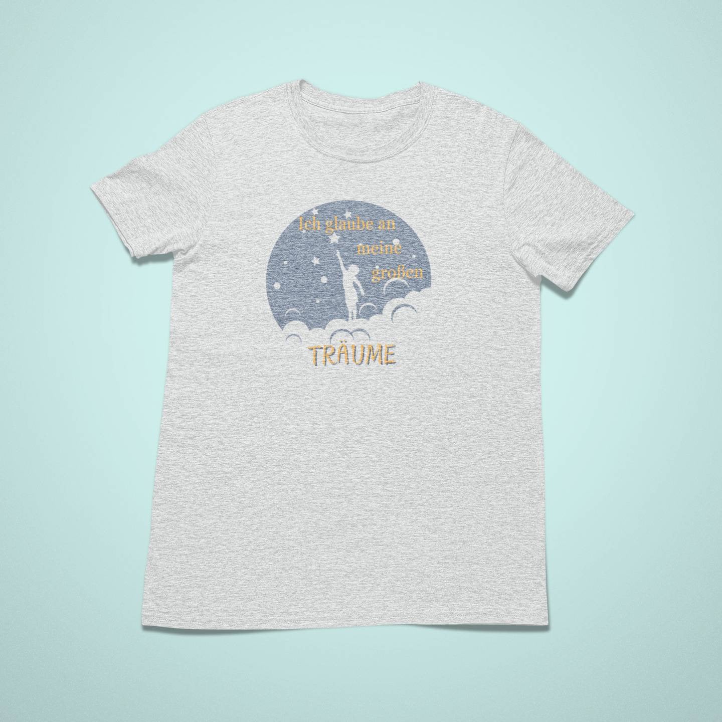 Hellgraues Kindershirt mit einem blauen Halbmond, in dem ein Kind nach einem Stern greift. Der Schriftzug „Ich glaube an meine großen TRÄUME“ ist in Gelb und Weiß gestaltet. Kleine Sterne umgeben die Szene.