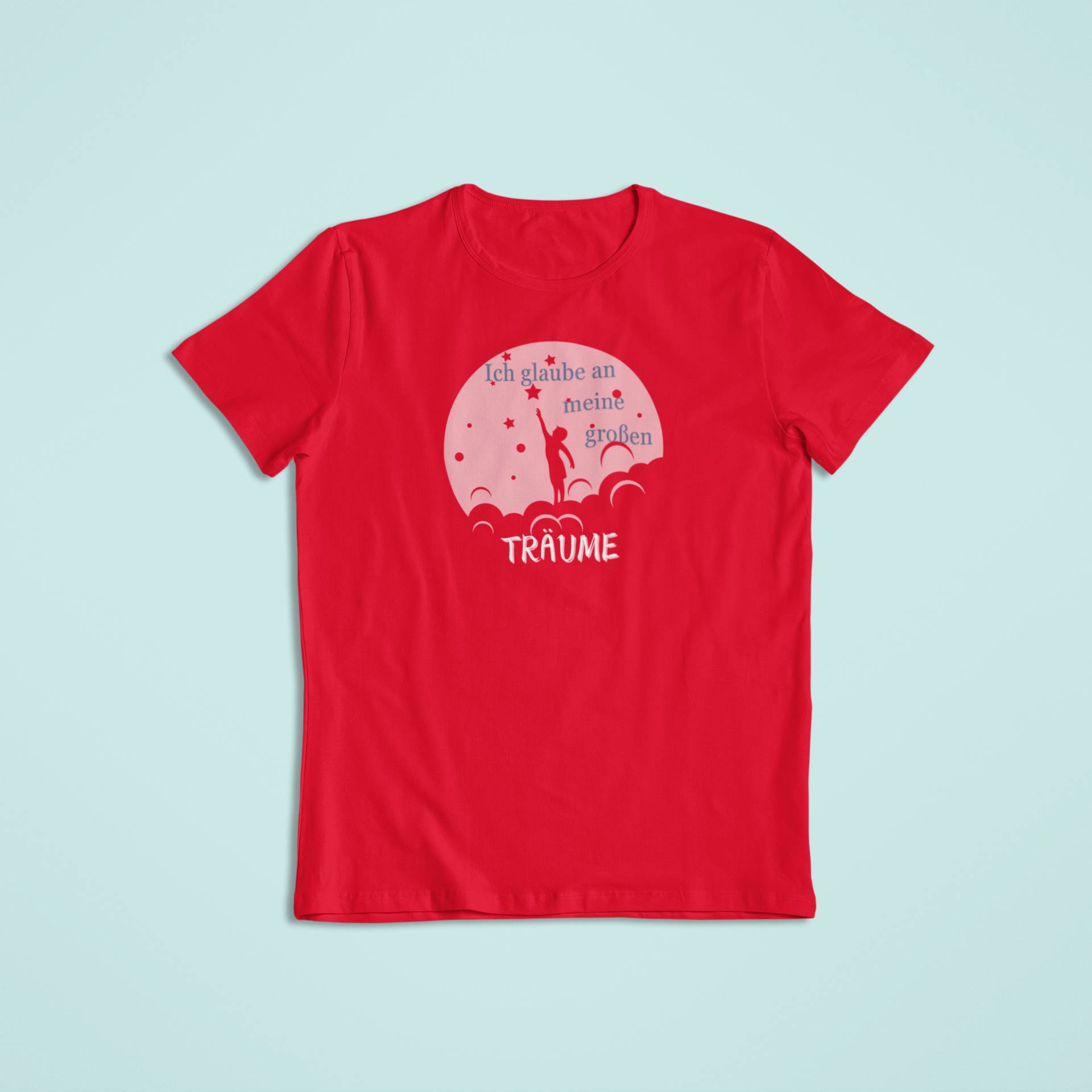 Rotes Kindershirt mit einem Design in Weiß und Hellrosa. Es zeigt eine Silhouette eines Kindes, das nach einem Stern greift, umgeben von Wolken. Darüber steht „Ich glaube an meine großen“ und darunter das Wort „TRÄUME“ in verspielter Schrift.