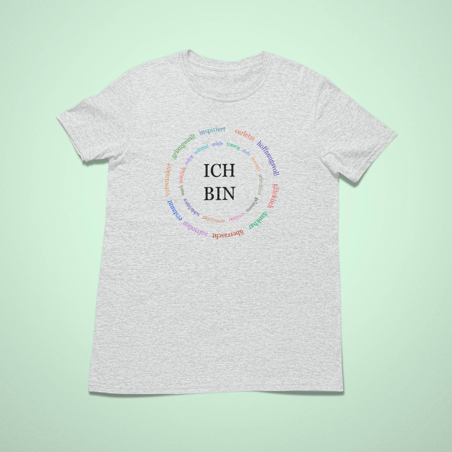 Kindershirt in Hellgrau mit einem bunten Kreis aus Affirmationen rund um die Worte „ICH BIN“ in der Mitte.