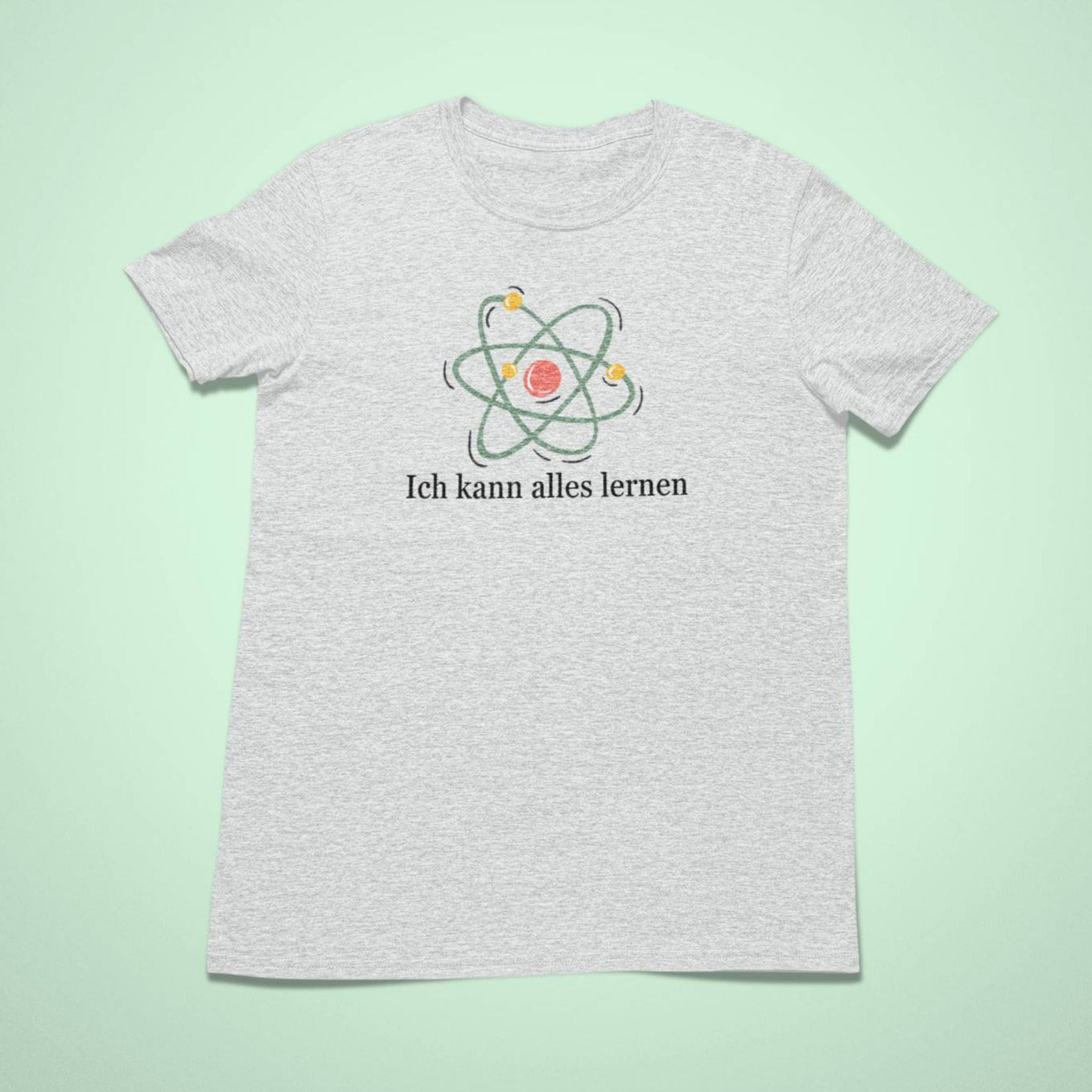 Hellgraues (Heather Grey) Kindershirt mit einem verspielten Atom-Symbol und dem Satz „Ich kann alles lernen“ in schwarzer Schrift darunter.