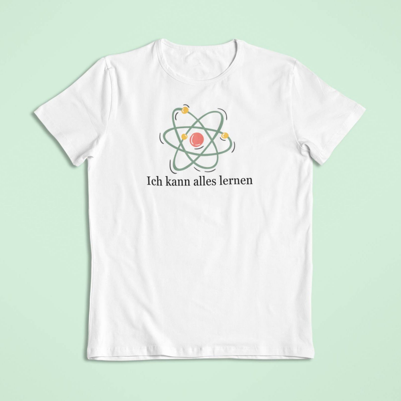 Weißes Kindershirt mit einem pastellfarbenen Atom-Symbol. Der Spruch „Ich kann alles lernen“ ist in schwarzer Schrift darunter gedruckt.