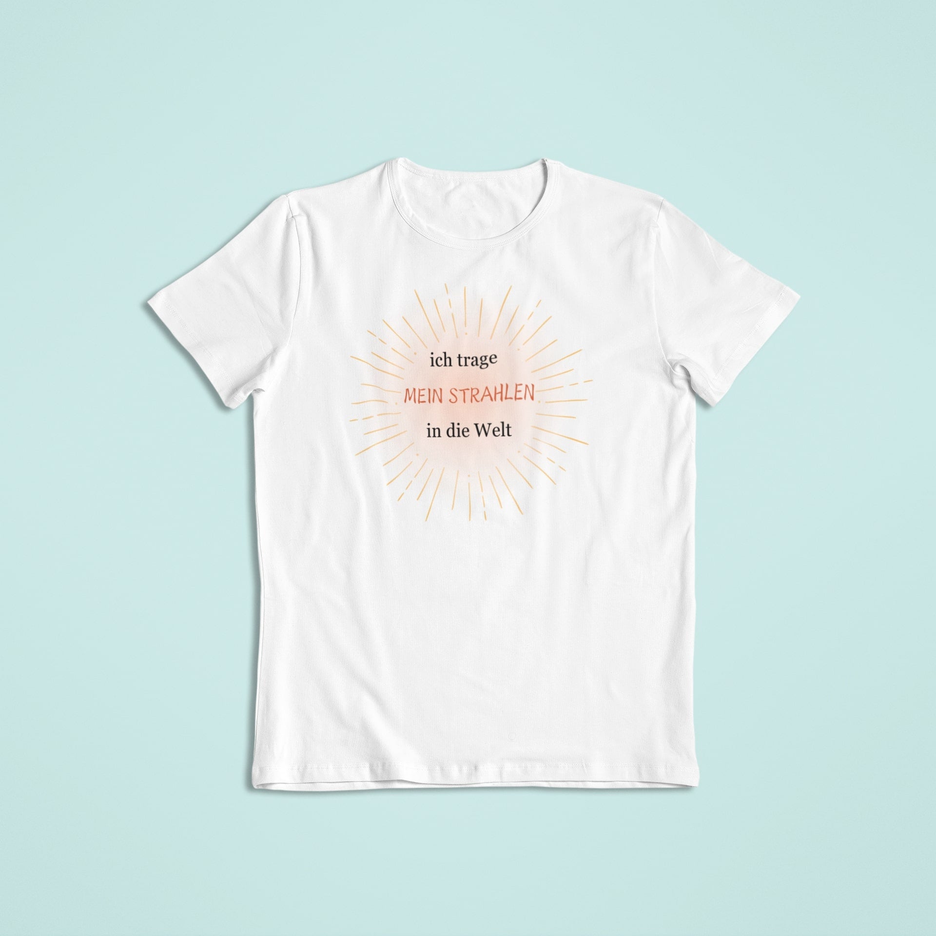 „Weißes Kindershirt mit orange-goldenem Strahlenmotiv und der Affirmation ‚ich trage MEIN STRAHLEN in die Welt‘ in Schwarz und Orange.“