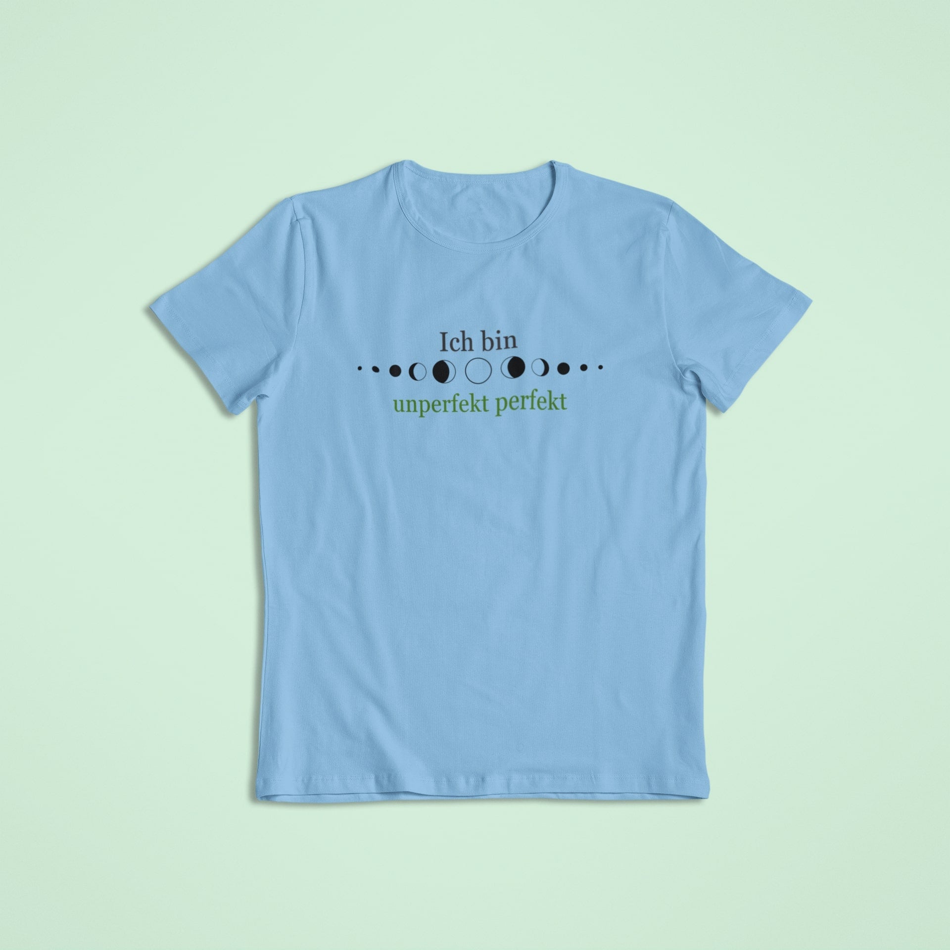 Kinderaffirmationsshirt in Himmelblau mit dem Spruch „Ich bin unperfekt perfekt“ in Schwarz und Grün, umgeben von stilisierten Mondphasen.