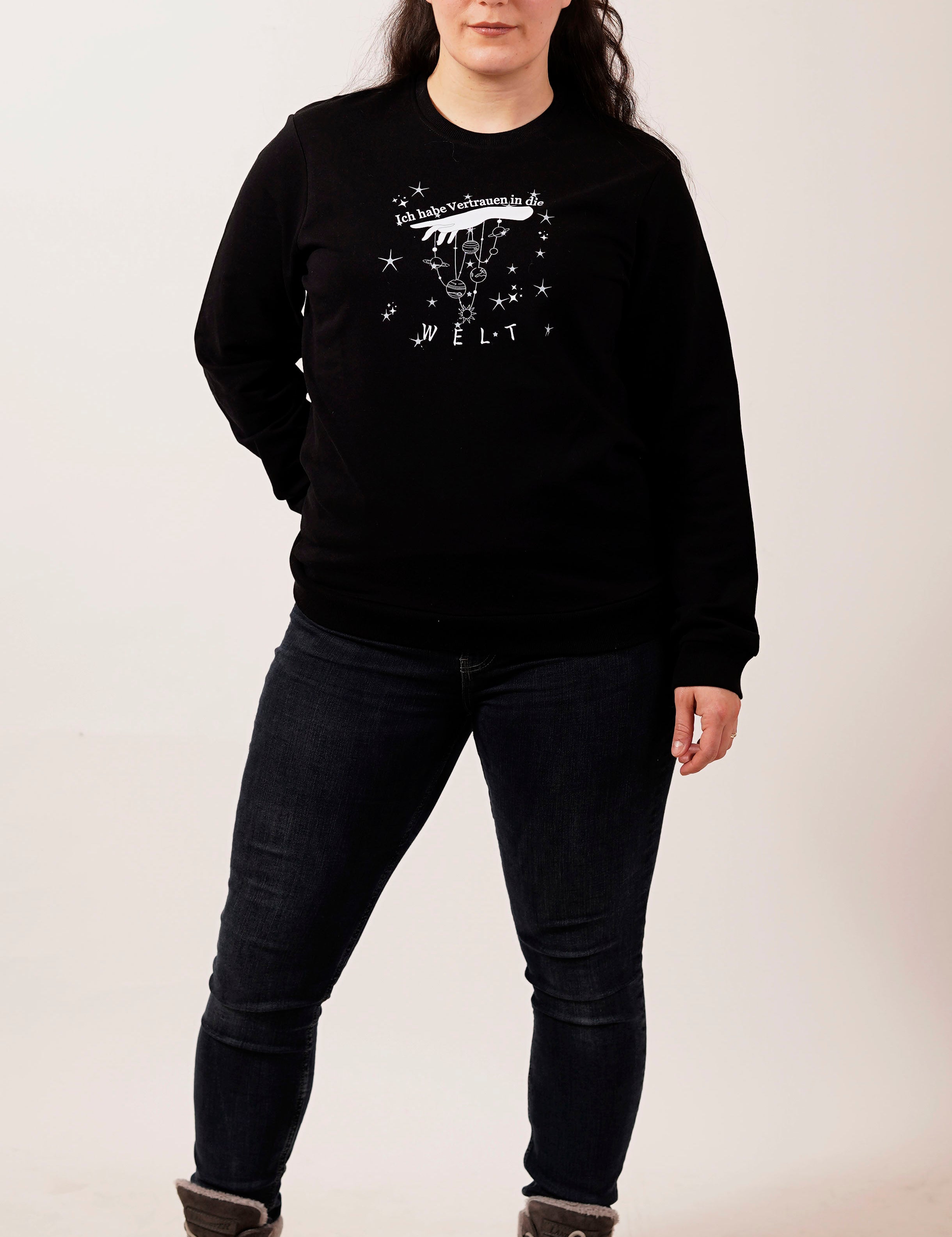 eine dame mit schwarzem pullover und weißer schrift ich habe vertrauen in die welt mit marionetten hand und planeten