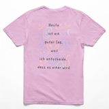Rückseite eines light-pinkes Kinder-T-Shirts mit farbenfrohem Smiley-Muster und dem Spruch: ‚Heute ist ein guter Tag, weil ich entscheide, dass es einer wird.‘