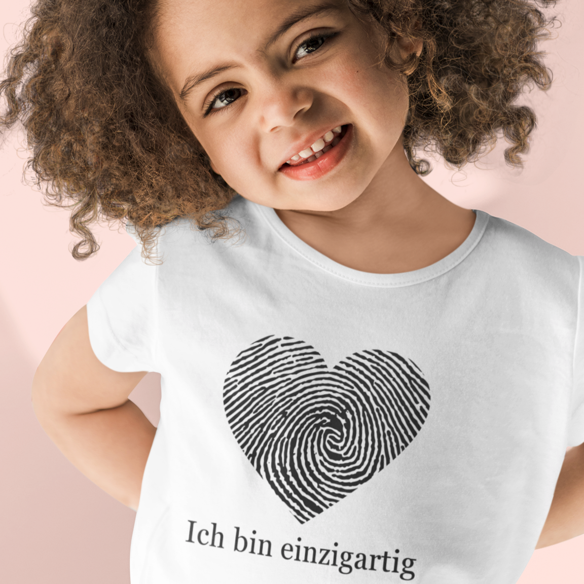 Weißes Affirmationsshirt für Kinder mit schwarzem Fingerabdruckherz und der positiven Aussage „Ich bin einzigartig“. Jedes Shirt ein Statement für Selbstliebe & Achtsamkeit.