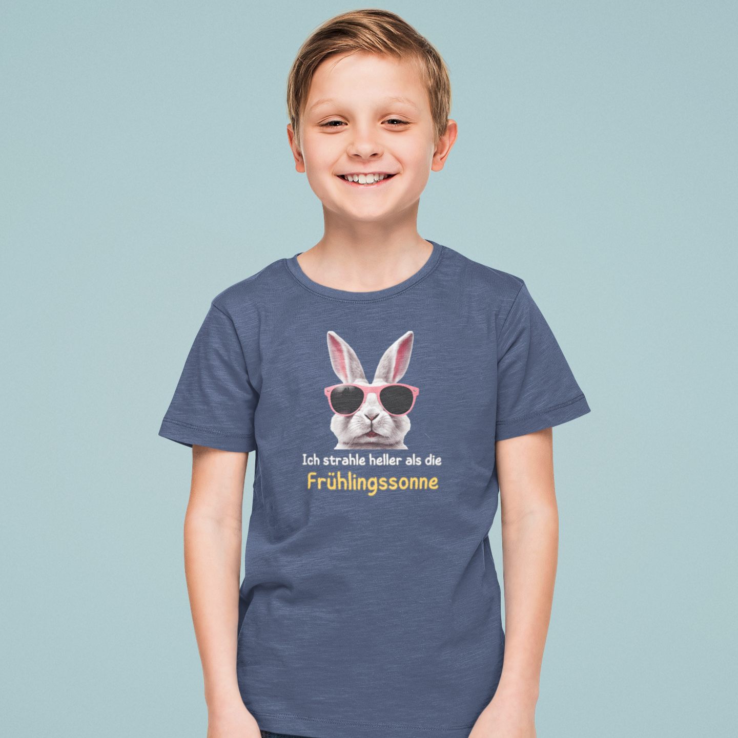 Lächelnder Junge trägt ein blaues Kinder-T-Shirt mit Hasenmotiv und Affirmation „Ich strahle heller als die Frühlingssonne“ – achtsame Frühlingsmode mit Botschaft für Kinder