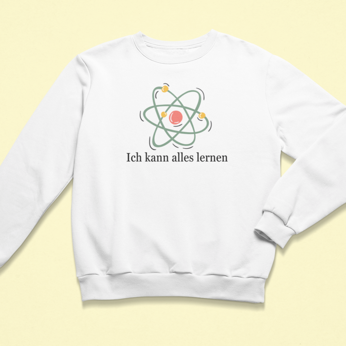 Weißes Kinder-Sweatshirt mit der Aufschrift „Ich kann alles lernen“ unter einer stilisierten bunten Atom-Grafik. Das Design vermittelt Neugier, Lernfreude und Wachstum.