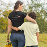 Mama mit Kind Arm in Arm auf einer Wiese, trägt schwarzes T-Shirt mit liebevollem Backprint über Mutterschaft aus der Kollektion „Achtsame Mama“ vom Sinachtsam-Shop