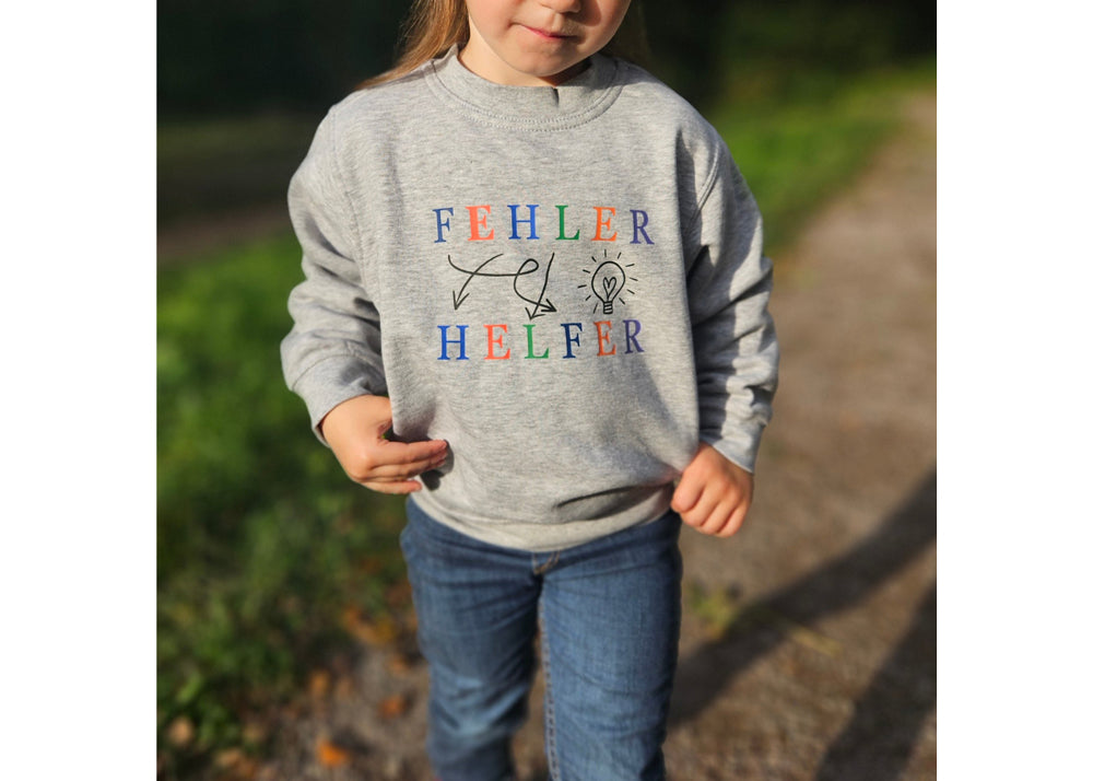 grauer pullover mit schwarzen icons und pfeilen, eine bunte schrift ziert Fehler Helfer