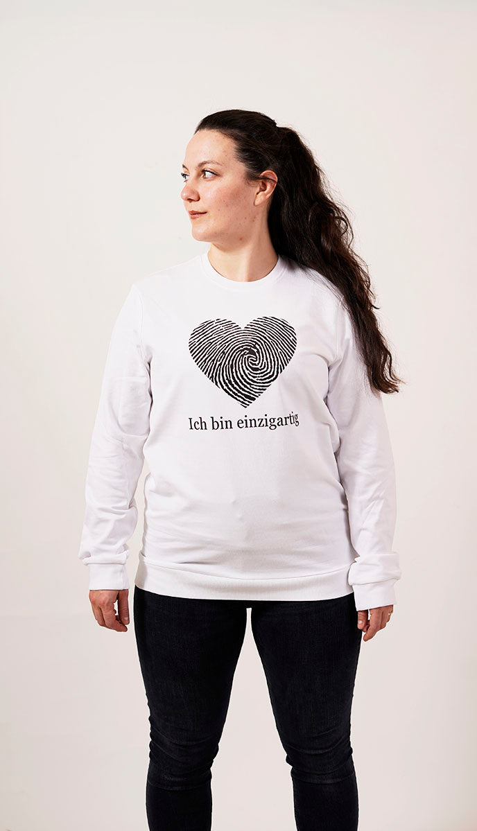 selbstbewusste frau in einem weißen pullover mit einem fingerabdruck in einer herz form und der schrift ich bin einzigartig für einzigartigkeit