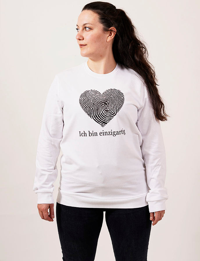 selbstbewusste frau in einem weißen pullover mit einem fingerabdruck in einer herz form und der schrift ich bin einzigartig für einzigartigkeit