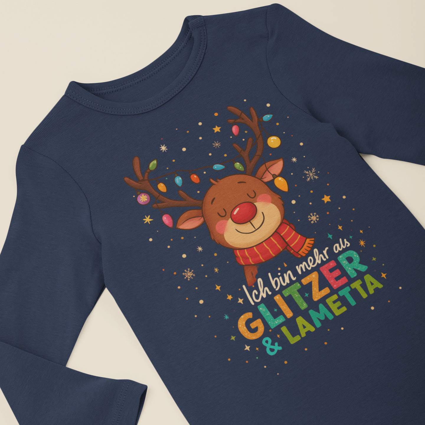 Navyfarbener Langarm-Body für Babys mit weihnachtlichem Rentier-Motiv und dem Spruch „Ich bin mehr als Glitzer und Lametta“, flach liegend vor neutralem Hintergrund.