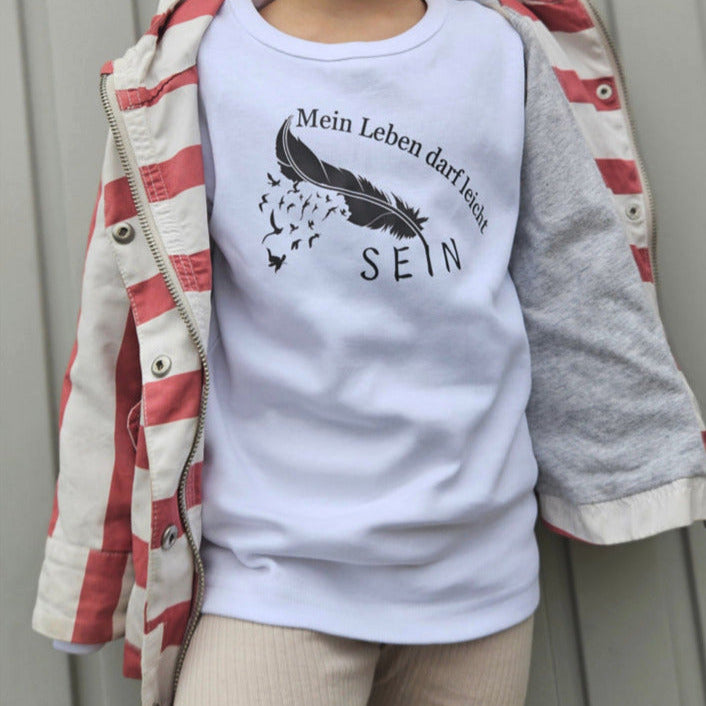 weißer kinder pullover mit schwarzer feder und schwarzem aufdruck mein leben darf leicht sein