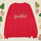 Alt-Text:
Rotes „Leuchten statt Leisten“ Sweatshirt, umgeben von Lebkuchenmännchen, Tannenbaumkeksen und Zuckerstangen.