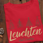 Rotes Weihnachtssweatshirt mit skizzierten grünen Tannenbäumen und dem Schriftzug „Leuchten statt Leisten“ – liebevoll gefertigt im Sinachtsam-Shop.