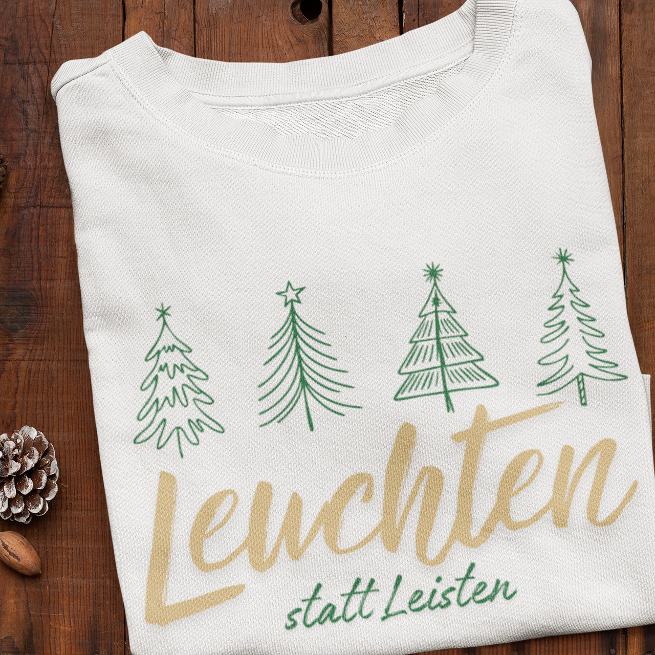 Weißes Weihnachtssweatshirt mit grünen Baumillustrationen und goldener Botschaft „Leuchten statt Leisten“ – nachhaltige Familienmode von Sinachtsam.