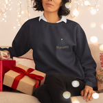 Frau sitzt vor Weihnachtslichtern auf dem Sofa und trägt ein dunkelblaues Sweatshirt mit Frontprint Präsenz und kleinem Geschenk-Symbol.