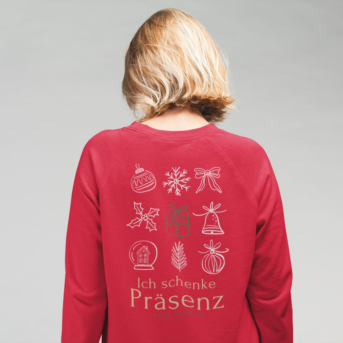 Frau trägt ein rotes Weihnachtssweatshirt mit großem Backprint aus weihnachtlichen Symbolen und dem Schriftzug Ich schenke Präsenz.