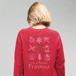 Frau trägt ein rotes Weihnachtssweatshirt mit großem Backprint aus weihnachtlichen Symbolen und dem Schriftzug Ich schenke Präsenz.