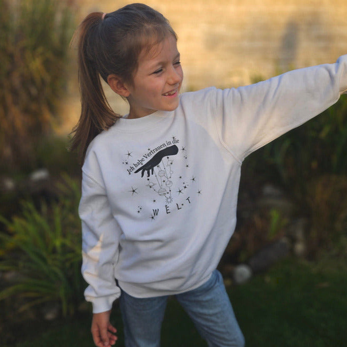 ein mädchen in einem weißen pullover mit schwarzer aufschrift ich habe vertrauen in die welt 